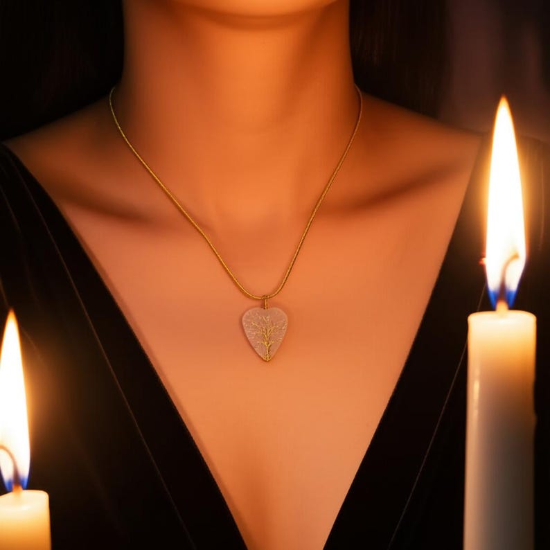 Handmade heart-shaped pendant featuring a natural white moonstone, wire-wrapped with a gold-tone tree of life design, on a black sweater.