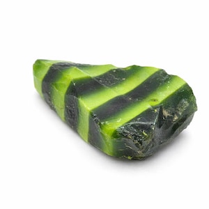 May include: A roughly shaped stone with a striped pattern of bright green and dark green bands. The stone has a natural, textured surface. The colour combination creates a striking visual contrast. The stone's shape is oblong.
