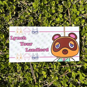 May include: A white rectangular sticker with the text "Lynch Your Landlord" in pink, featuring cartoon animal characters. The sticker includes a cartoon character with a noose around its neck.