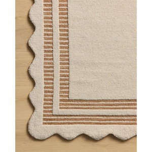 Könnte beinhalten: Cremefarbene rechteckige Badematte mit gewelltem Rand. Die Matte hat einen Rand aus braunen Streifen und einen passenden Innenrand. Die weiche, strukturierte Oberfläche verleiht jedem Badezimmer einen Hauch von Eleganz.