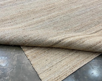 Alfombra de yute tejida a mano en color beige arena, con tejido grueso y texturizado.