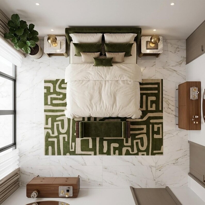 Puede incluir: Una vista cenital de un dormitorio con una cama que tiene un edred&oacute;n color crema, almohadas verde oliva y un banco a juego. La cama se asienta sobre una alfombra grande con un patr&oacute;n geom&eacute;trico verde y crema, rodeada de suelo de m&aacute;rmol blanco.