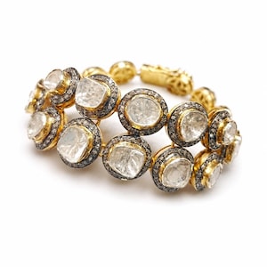 Puede incluir: Una pulsera de varias filas con numerosos diamantes de talla rosa engastados en bisel. Cada diamante está encerrado en un engaste de plata oxidada oscura con un borde dorado, unidos por eslabones de oro para formar una cadena flexible.