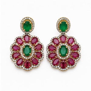 May include: A pair of gold earrings featuring a central oval emerald surrounded by a ring of oval rubies and a border of small white diamonds. A single oval emerald sits at the top of each earring, framed by a halo of small white diamonds.