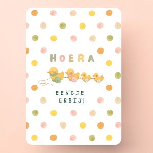 May include: A rectangular card with a white background and colorful polka dots. The card features a watercolor illustration of a duckling train and the text "HOERA" and "EENDJE ERBIJ!"