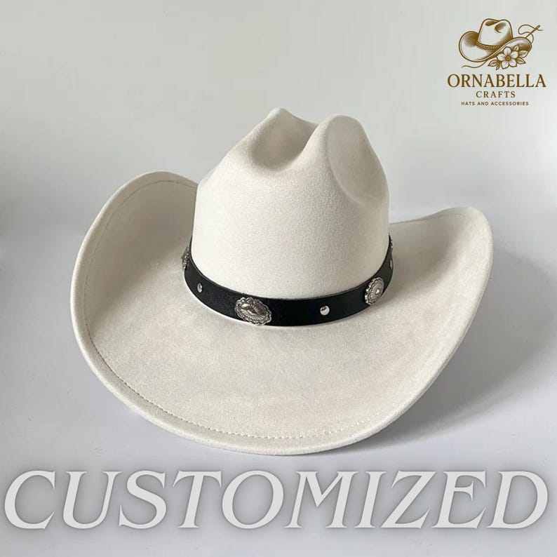 May include: A white cowboy hat with a black band adorned with silver-colored decorative elements. The hat has a wide brim and a classic crown shape. The word "CUSTOMIZED" is displayed at the bottom of the image.