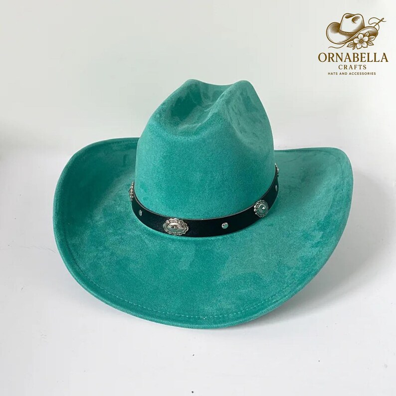 May include: A turquoise cowboy hat with a black band adorned with silver-colored embellishments. The hat has a wide brim and a classic western design. The hat is made of a soft material.