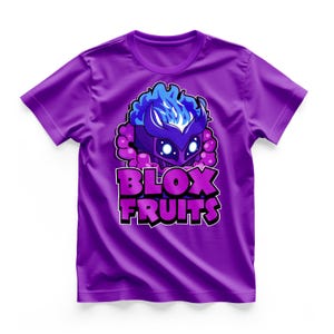 May include: Purple t-shirt featuring a graphic of a character with a blue flame-like design and the text "BLOX FRUITS" in purple and white. The shirt is a solid purple color.