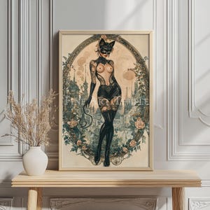 May include: A framed vintage-style print featuring a woman in a cat mask and costume, set against a backdrop of a city and floral elements. The artwork has a vintage aesthetic with soft colors and intricate details.