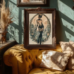 May include: A framed artwork featuring a woman in a cat-themed costume, set against a cityscape and floral border. The artwork is in a dark wooden frame, displayed on a yellow sofa. The room has a vintage aesthetic.