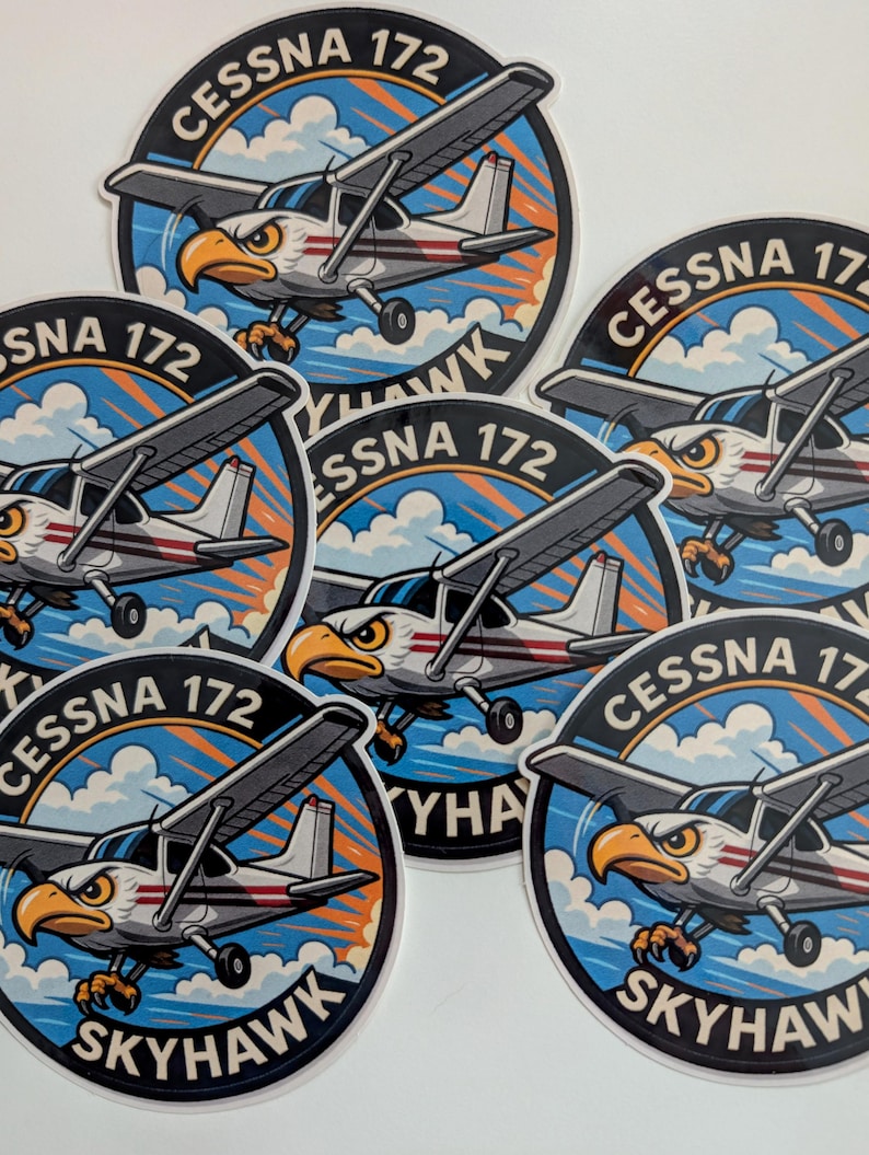 May include: A collection of round stickers featuring a Cessna 172 Skyhawk airplane with an eagle head design. The stickers have a blue and orange sky background with the text "CESSNA 172 SKYHAWK".