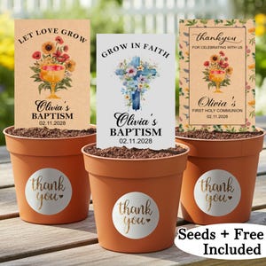 Op de afbeelding: Drie terracotta potten met gepersonaliseerde zaadzakjes voor een doop en eerste communie. De zakjes hebben bloemmotieven en tekst als "Let Love Grow". Elke pot heeft een "thank you" sticker.