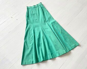 May include: A long, flowing green skirt with a fitted waist and a flared hem. The skirt is made of a lightweight fabric and has a simple, elegant design.