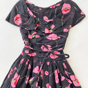 Peut inclure: Une robe noire &agrave; imprim&eacute; floral rose et un n&oelig;ud &agrave; la taille.