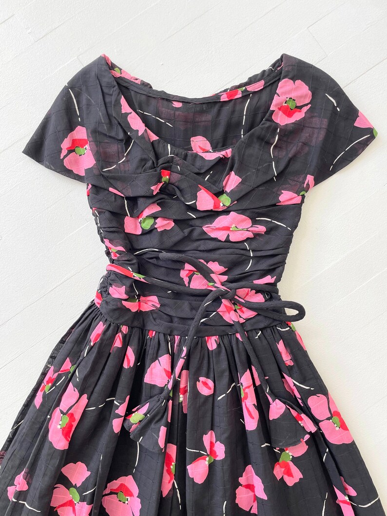 Peut inclure: Une robe noire &agrave; imprim&eacute; floral rose et un n&oelig;ud &agrave; la taille.