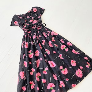 Peut inclure: Une robe noire et rose &agrave; fleurs avec un corsage ajust&eacute; et une jupe ample. La robe a un d&eacute;collet&eacute; en c&oelig;ur et des manches courtes. Le corsage pr&eacute;sente un la&ccedil;age sur le devant.