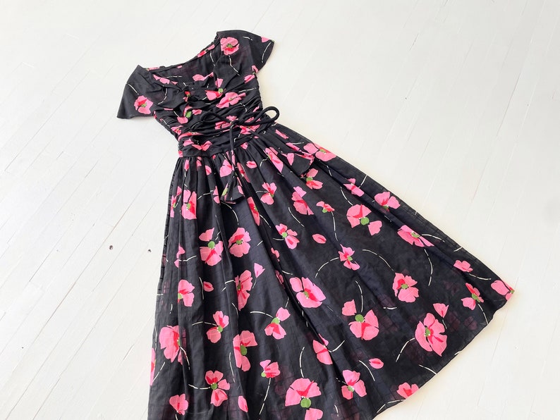 Peut inclure: Une robe noire et rose &agrave; fleurs avec un corsage ajust&eacute; et une jupe ample. La robe a un d&eacute;collet&eacute; en c&oelig;ur et des manches courtes. Le corsage pr&eacute;sente un la&ccedil;age sur le devant.