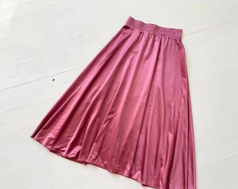 May include: A long, flowing skirt in a dusty rose color. The skirt has an elastic waistband and a smooth, silky texture.