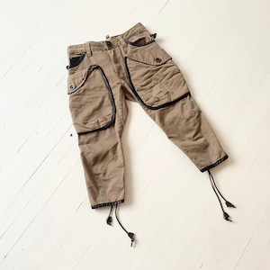 May include: A pair of khaki cargo pants with black trim and drawstrings at the bottom.