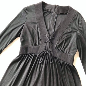 May include: A black long-sleeved dress with a V-neck and a lace-up detail at the bodice.