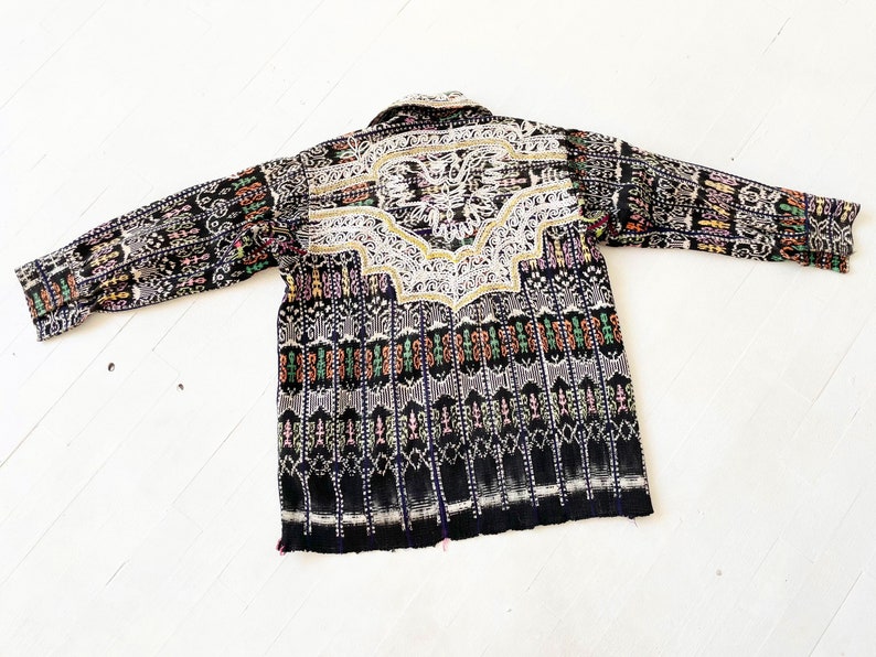 Puede incluir: Una camisa de manga larga negra y blanca con un patr&oacute;n geom&eacute;trico colorido y un dise&ntilde;o bordado blanco en la espalda.