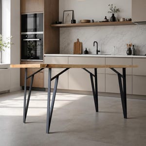 May include: A rectangular wooden dining table with black metal legs. The table has a light brown tabletop and a modern design. The legs are angled and provide support. The table is in a kitchen setting.