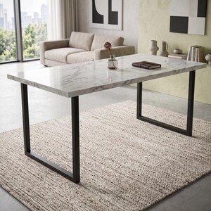 Peut inclure: Une table à manger rectangulaire dotée d'un plateau en faux marbre blanc avec des veines grises et d'un cadre robuste en métal noir avec deux pieds en forme de U. La surface de la table est lisse et polie, offrant un aspect épuré.