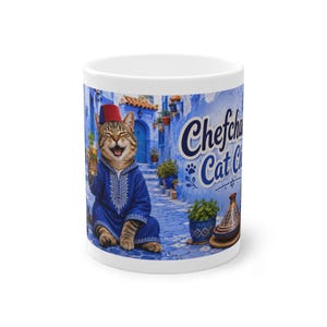 May include: A white ceramic mug featuring a graphic of a tabby cat wearing a blue djellaba and a red fez, holding a glass of mint tea. The background shows blue-walled buildings and the text Chefchaouen Cat Club in dark blue script.