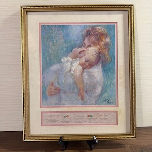 May include: A framed print featuring an impressionistic painting of a person holding a sleeping baby, set against a blue background. Below the image, a pink rectangular panel contains the poem Only a Baby Small in black text with floral accents.