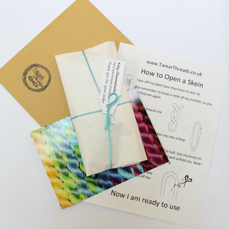 May include: A craft package containing a skein of yarn wrapped in paper and tied with teal string. The package includes a brown envelope with a logo and instructions on how to open the skein, with the website address www.TamarThreads.co.uk.