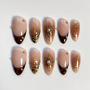Puede incluir: Juego de diez uñas postizas en forma de almendra. Las uñas presentan una base nude con varios diseños, incluyendo soles dorados, adornos dorados y una punta de estampado de leopardo marrón oscuro. Cada uña está adornada con pequeños tachuelas doradas.