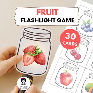 Puede incluir: Un juego de linterna con temática de frutas con 30 cartas. El juego presenta ilustraciones de frutas dentro de tarros de cristal. Una tarjeta muestra fresas. El texto "FRUIT FLASHLIGHT GAME" está en la parte superior.