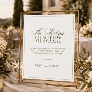 May include: A rectangular memorial sign in a thin gold metal frame. The white sign features dark green text reading In Loving Memory of all those who could not be here today, but who remain forever in our hearts. Today and always. Olivia & James.