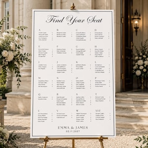 May include: A white wedding seating chart sign with black text featuring the heading Find Your Seat, an alphabetical list of names with table numbers, and the names Emma & James with the date 03.11.2027 at the bottom, displayed on a stand.