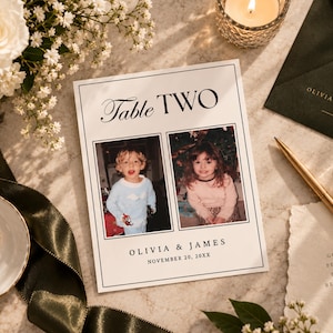 May include: A white rectangular table number card featuring the text Table TWO, two square photographs of children, and the names Olivia & James with the date November 20, 20XX printed in black ink with a thin black border frame.