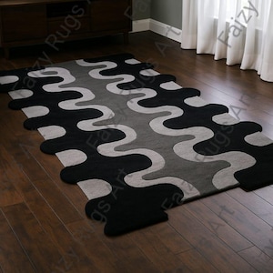 May include: A modern area rug with a wavy pattern in black, gray, and light gray. The rug is rectangular with rounded edges and is placed on a dark hardwood floor. The rug's design adds a contemporary touch to the room.