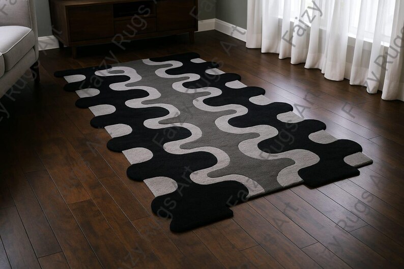 May include: A modern area rug with a wavy pattern in black, gray, and light gray. The rug is rectangular with rounded edges and is placed on a dark hardwood floor. The rug's design adds a contemporary touch to the room.