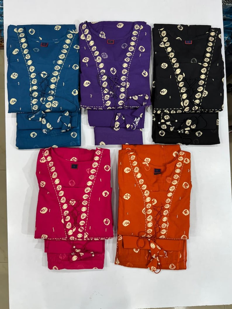 May include: Five sets of matching pajamas in various colors: teal, purple, black, hot pink, and orange. Each set features a top with a lace-up neckline and a repeating white circular pattern, paired with matching pants.