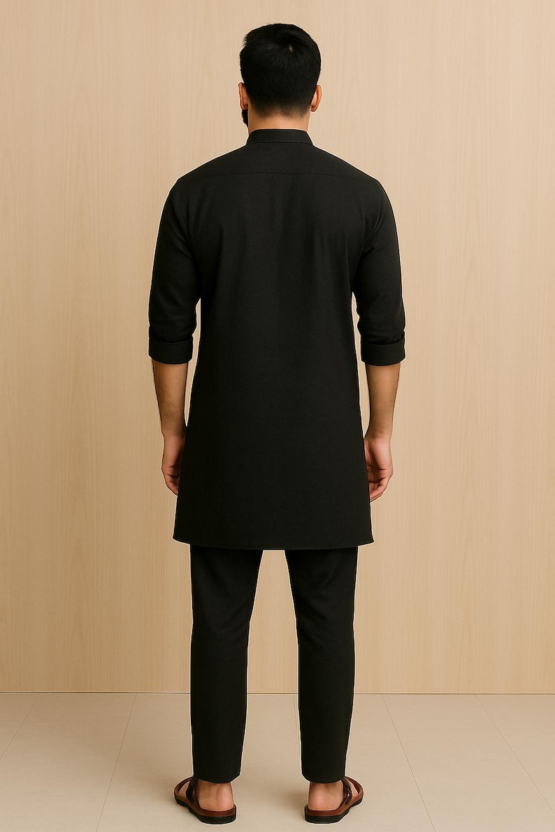 Puede incluir: Conjunto negro de camisa t&uacute;nica de manga larga y pantal&oacute;n a juego. La t&uacute;nica tiene cuello mandar&iacute;n y dobladillo recto. El pantal&oacute;n es de corte recto. El conjunto es de tela negra lisa. El modelo lleva sandalias marrones.