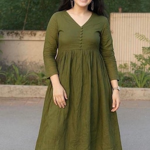 Peut inclure: Une robe vert olive &agrave; manches longues et col en V. La robe pr&eacute;sente un devant boutonn&eacute; et une taille fronc&eacute;e, associ&eacute;e &agrave; un pantalon assorti. La tenue est faite d'un tissu doux et fluide.