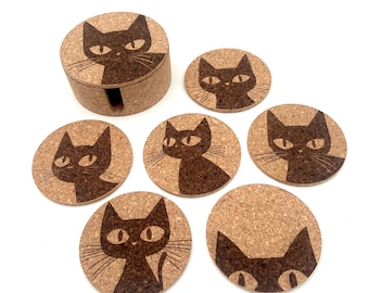 May include: A set of cork coasters with a matching holder. Each coaster features a black cat design. The coasters are round and the holder is cylindrical. The cat design is a simple, stylized illustration.