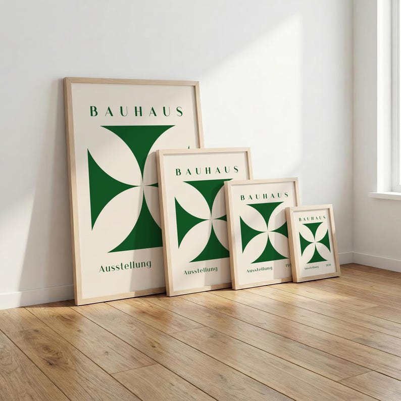 May include: Four framed Bauhaus art prints in varying sizes lean against a white wall. Each print features a green geometric design and the word "BAUHAUS" at the top. The word "Ausstellung" is printed at the bottom of each print.