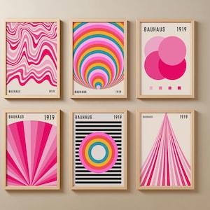 Könnte beinhalten: Sechs gerahmte Bauhaus-Kunstdrucke. Die Drucke zeigen geometrische Designs in Pink, Rot, Gelb und Blau. Jeder Druck ist in einem hellen Holzrahmen und enthält den Text "BAUHAUS 1919". Die Designs umfassen wellenförmige Linien, konzentrische Kreise und geometrische Formen.