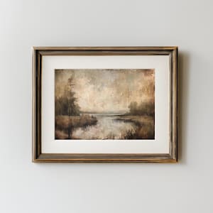May include: A framed landscape painting with a serene river scene. The artwork features muted tones of brown, beige, and gray, with a textured appearance. The frame is a dark brown with a gold trim, adding a touch of elegance to the artwork.