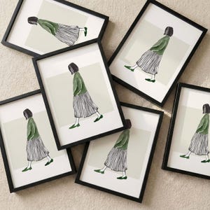 Könnte beinhalten: Eine Sammlung gerahmter Kunstdrucke mit einer minimalistischen Illustration einer Person beim Gehen. Jeder Druck in einem schwarzen Rahmen zeigt eine Figur in einem grünen Oberteil, gestreiften Rock und grünen Schuhen vor hellgrünem Hintergrund.