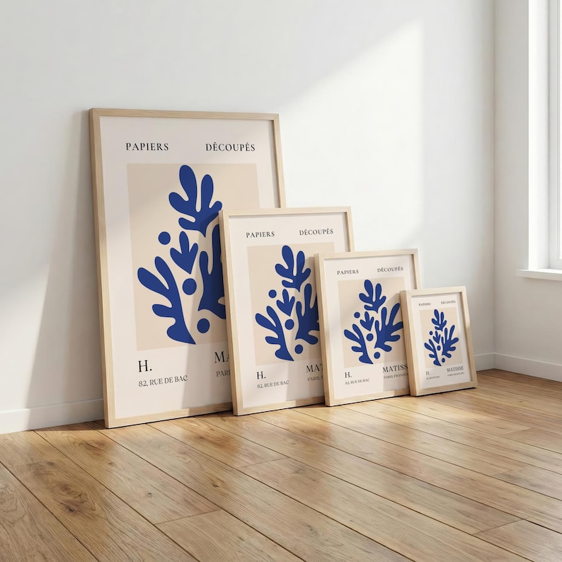 May include: A set of four framed art prints featuring a blue abstract design on a cream background. The prints are in varying sizes and have a light wood frame. Text includes "PAPIERS D&Eacute;COUP&Eacute;S" and "MATISS".