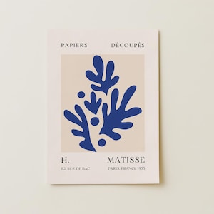 May include: A rectangular art print featuring a blue abstract design on a beige background. The print includes the text "PAPIERS DÉCOUPÉS" at the top and "MATISSE PARIS, FRANCE 1955" at the bottom. The address "82, RUE DE BAC" is also included.