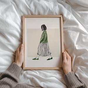 Könnte beinhalten: Ein gerahmter Kunstdruck mit einer Aquarellillustration einer Person, die geht. Die Figur trägt eine grüne Jacke, einen gestreiften Rock und grüne Schuhe. Das Kunstwerk hat einen minimalistischen Stil mit einer neutralen Farbpalette.