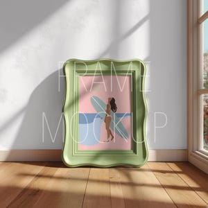 Peut inclure: Une impression d'art encadrée représentant une femme avec une planche de surf. L'œuvre d'art a un fond rose et bleu avec un cadre vert clair. Le texte "FRAME MOCKUP" est imprimé sur le cadre.