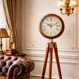 May include: A vintage-style floor clock with a round, light-colored face and Roman numerals. The clock is set in a dark wood frame and mounted on a tripod stand with brass accents. The clock face reads "London".
